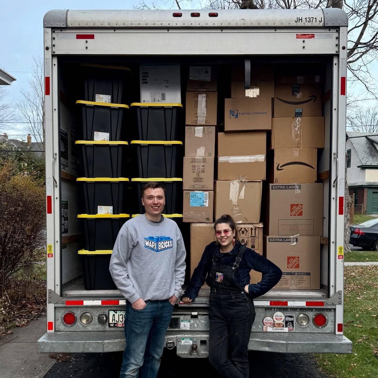Zach and Adrienne in front of a moving truck filled by a major LEGO collection
